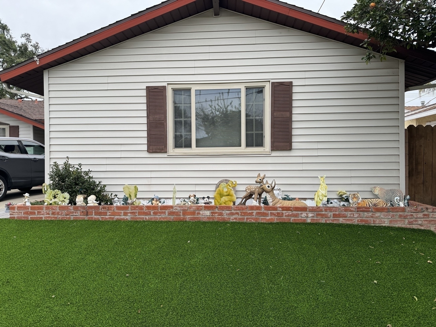 Pleasing rectangular arrangement of the white front exterior wall of a suburban house with a green lawn in front. 